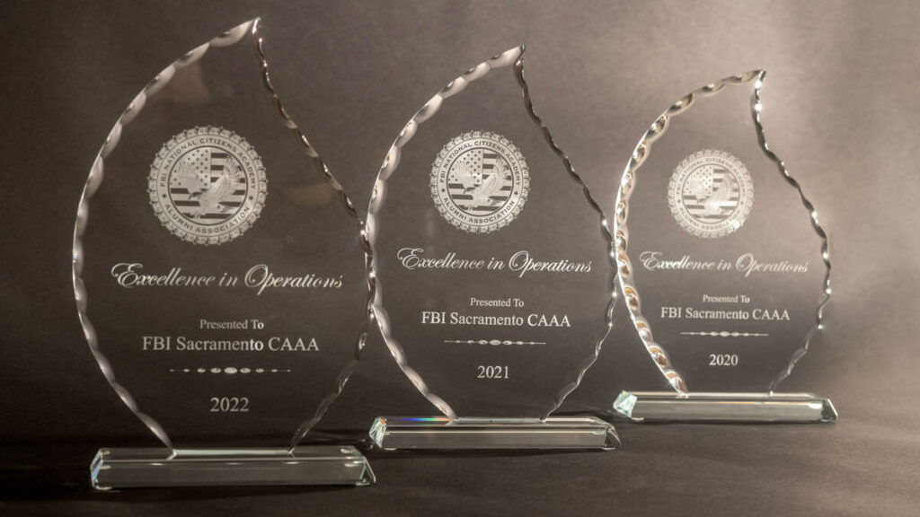 Three crystal awards shaped like irregular teardrops, positioned in a staggered row, each for Excellence in Operations.